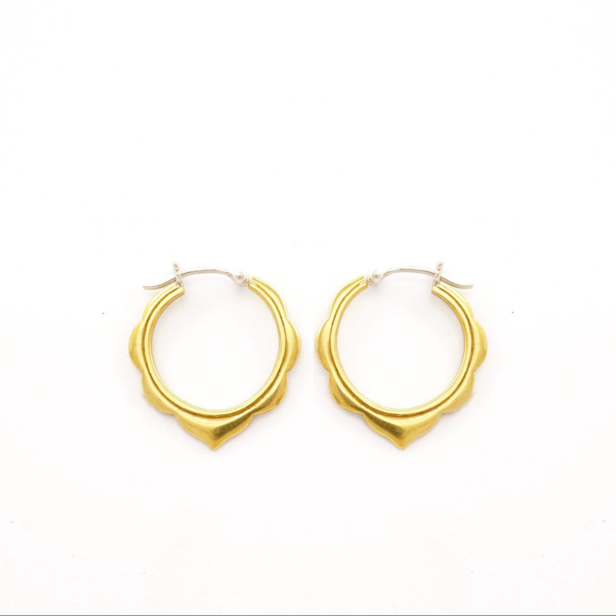 May include: A pair of gold-colored hoop earrings with a scalloped design. The earrings have a smooth, matte finish and a silver-colored clasp. The earrings are displayed on a white background.